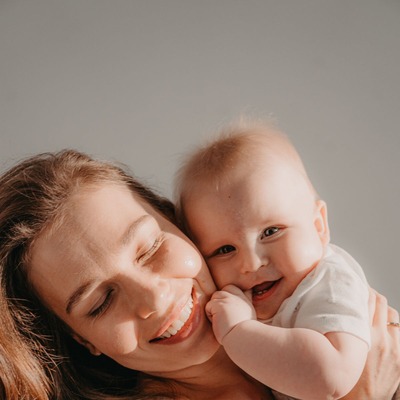 Sarah M., experienced surrogate mother smiling tenderly with her baby - Harmony Surrogacy